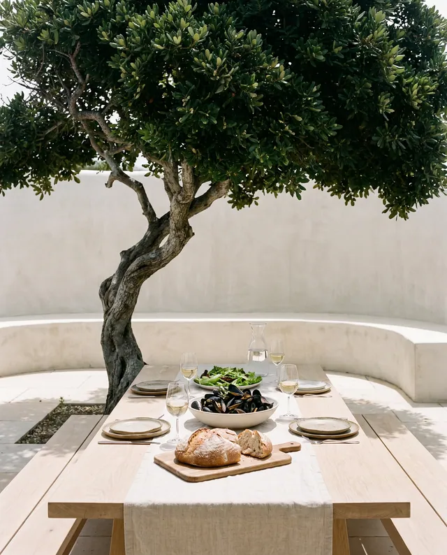 Lunch laid on an oak table under the old tree in the courtyard: mussels, bread, a salad and white wine